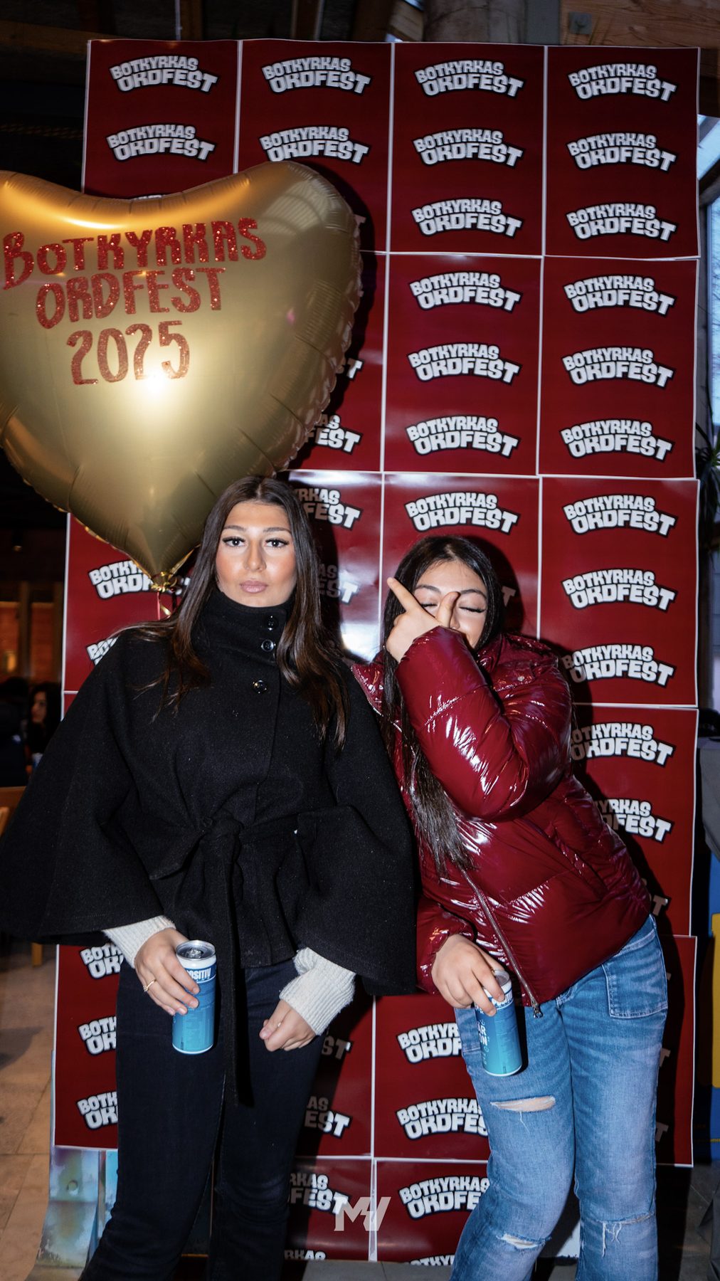 Två glada deltagare framför Ordfests vinröda logotypvägg med en guldfärgad hjärtballong märkt Botkyrkas Ordfest 2025.