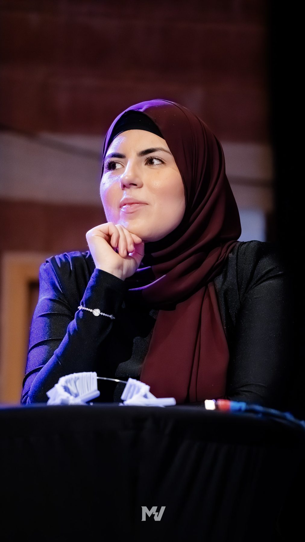 En jurymedlem i vinröd hijab lyssnar koncentrerat under prisgalan.