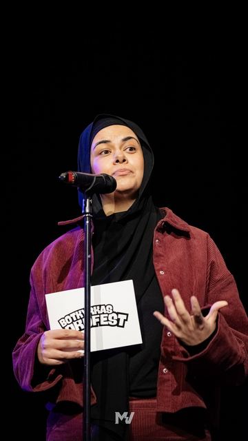 Konferencieren håller upp ett kort med Botkyrkas Ordfest-logotypen på scen.